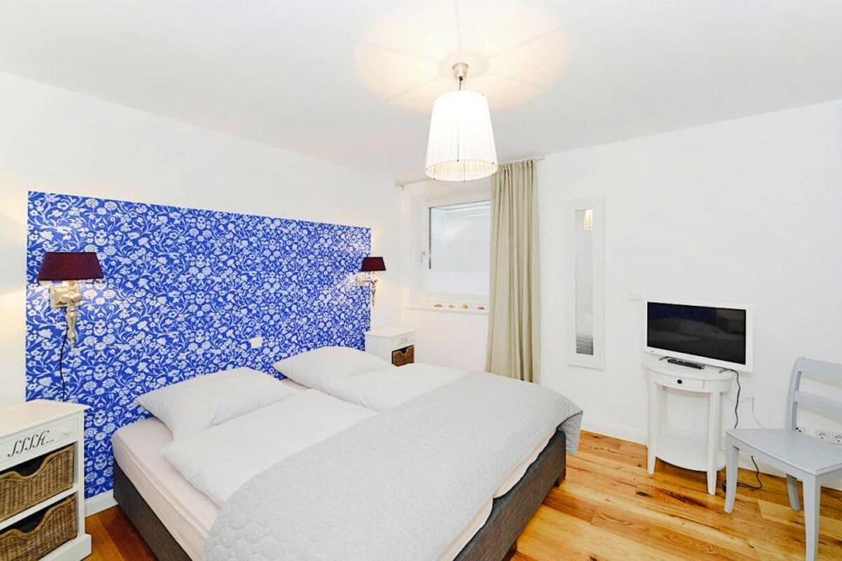 A bedroom with a large bed, a TV, and a desk.