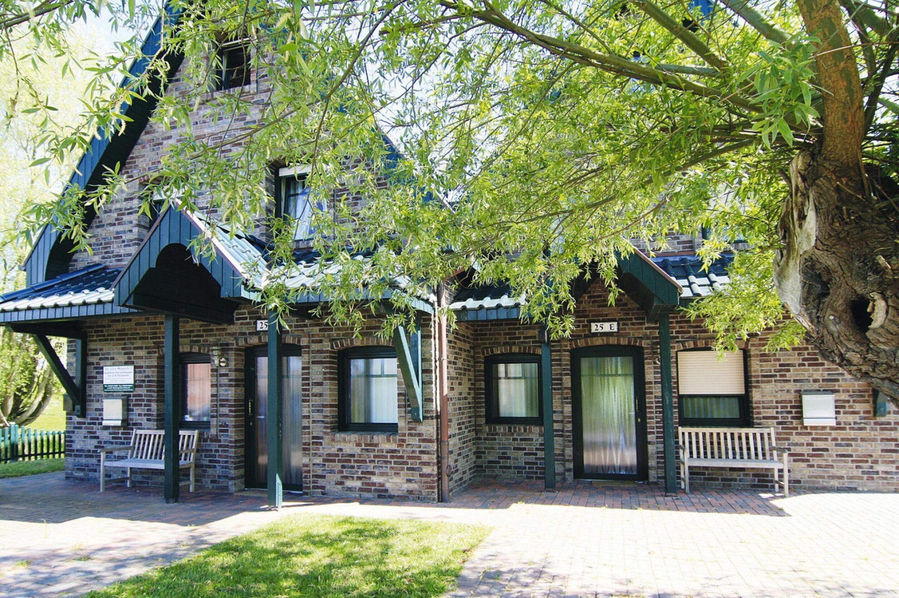 A brick building with a sloped roof, two doors, and a bench outside.