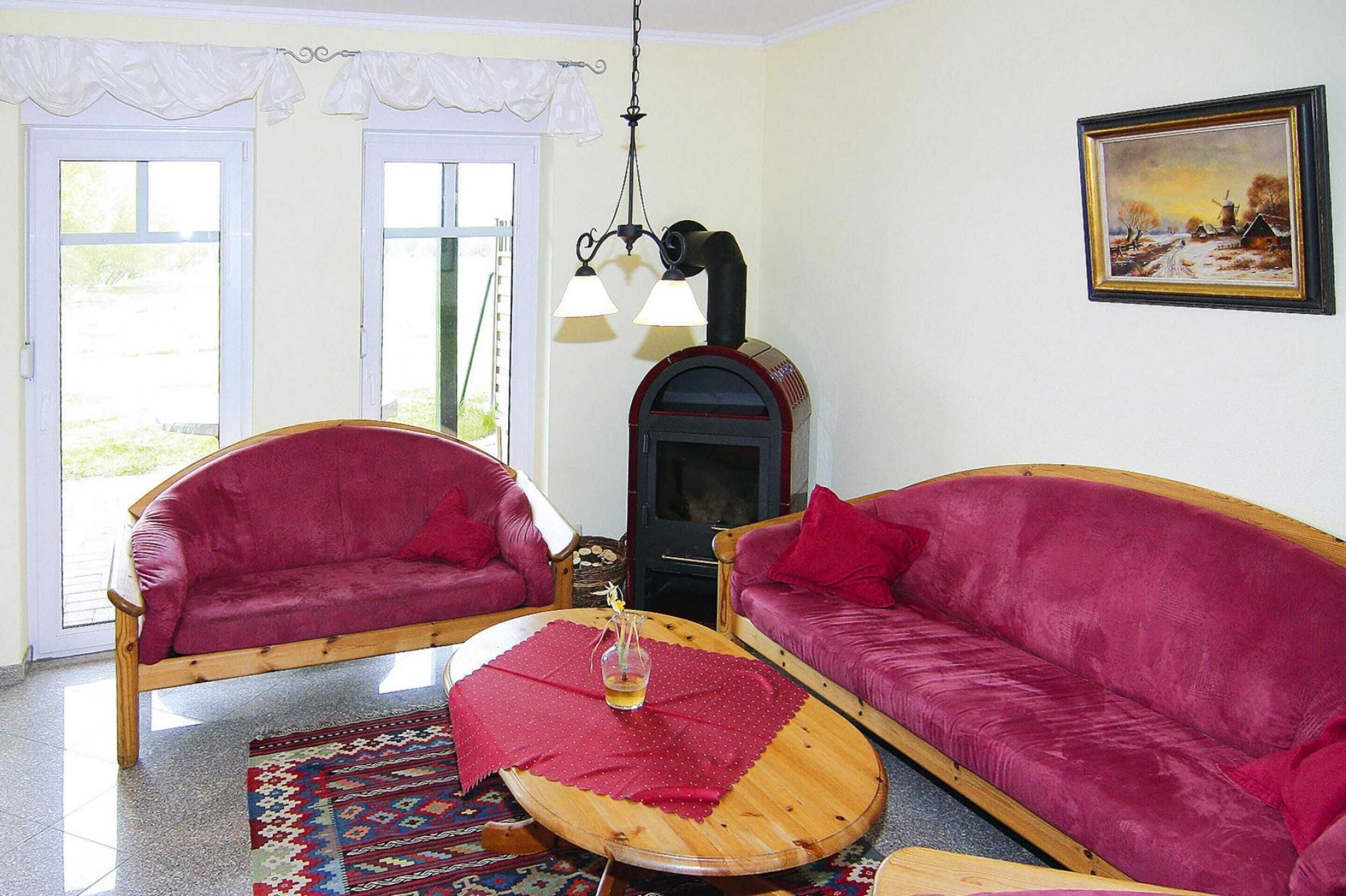 Un salon avec deux canapés rouges, une table basse en bois, une cheminée et un tableau accroché au mur.