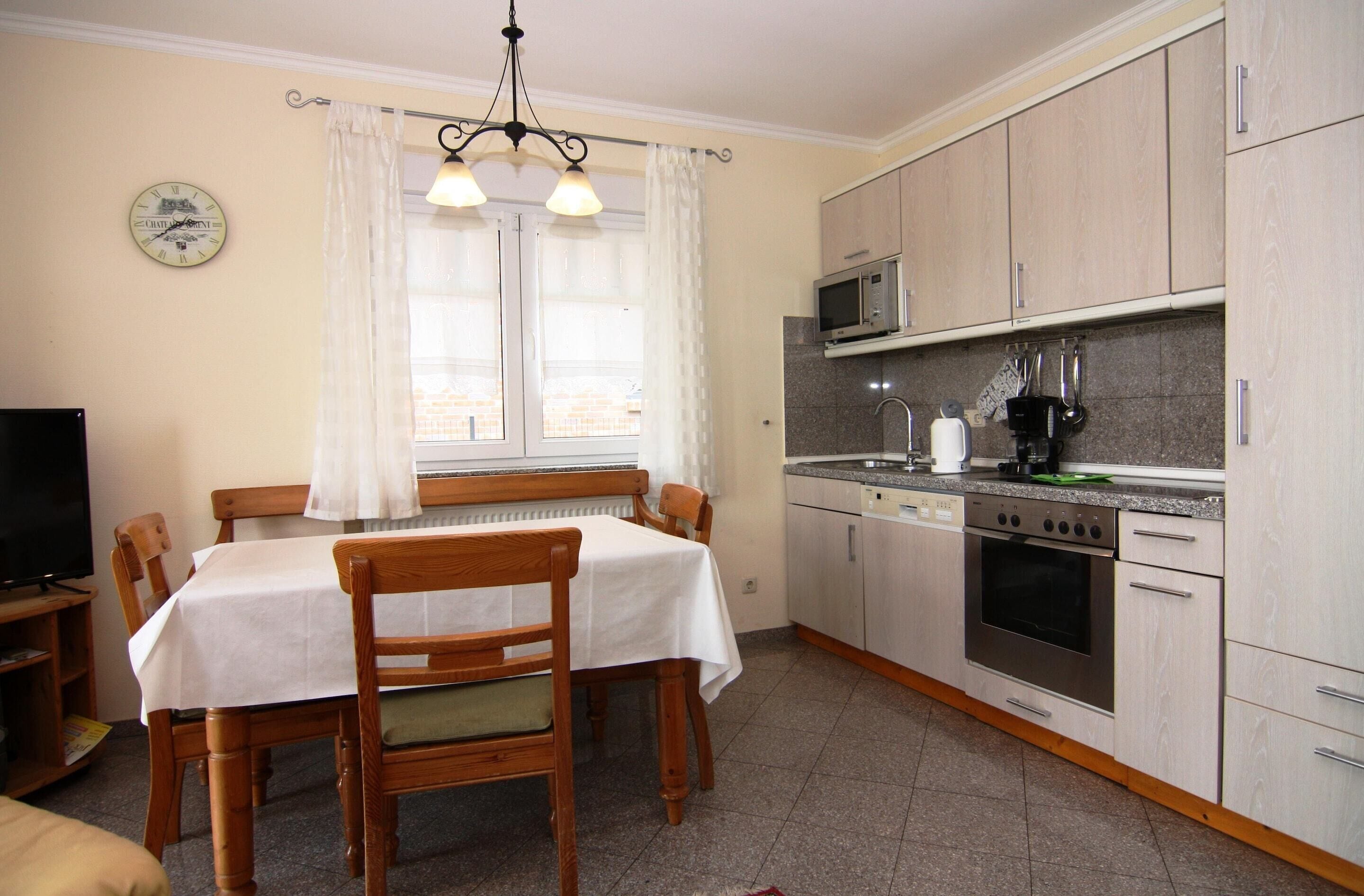 Una cocina compacta con área de comedor, que incluye un microondas, estufa y un reloj en la pared.