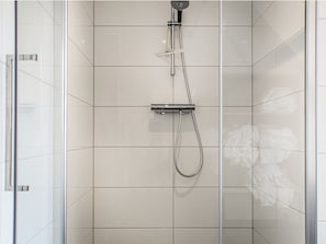 Zona de ducha con paredes de vidrio, ducha de mano y ducha fija.