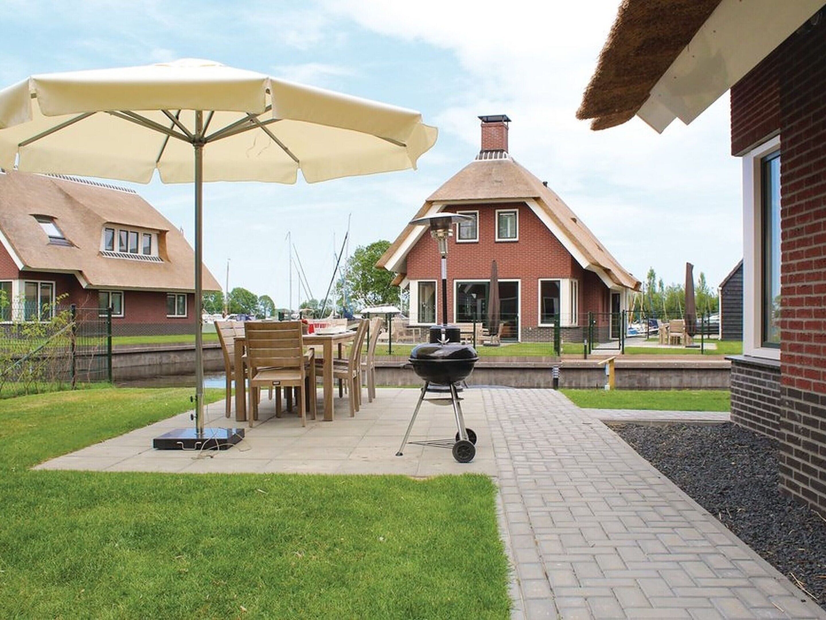 A patio area with a table and chairs, a barbecue grill, and umbrellas.