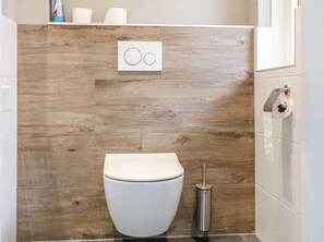 A modern bathroom with a wooden wall, a toilet, a bidet, and a toilet paper holder.