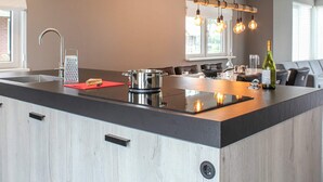 Una cocina moderna con una isla grande, electrodomésticos de acero inoxidable y una lámpara colgante.