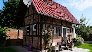 A traditional half-timbered house with a red tiled roof, a satellite dish, and a small outdoor seating area with a staircase leading to the entrance. - Holiday Home, Kolczewo (gmina Wolin)