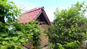 A small wooden structure with a red roof, surrounded by lush greenery. - Holiday Home, Kolczewo (gmina Wolin)