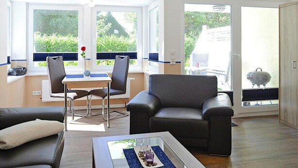 A modern living room with a sofa, a coffee table, and a dining area with chairs and a table. - Apartment House, Wyk auf Foehr (Wyk auf Foehr)