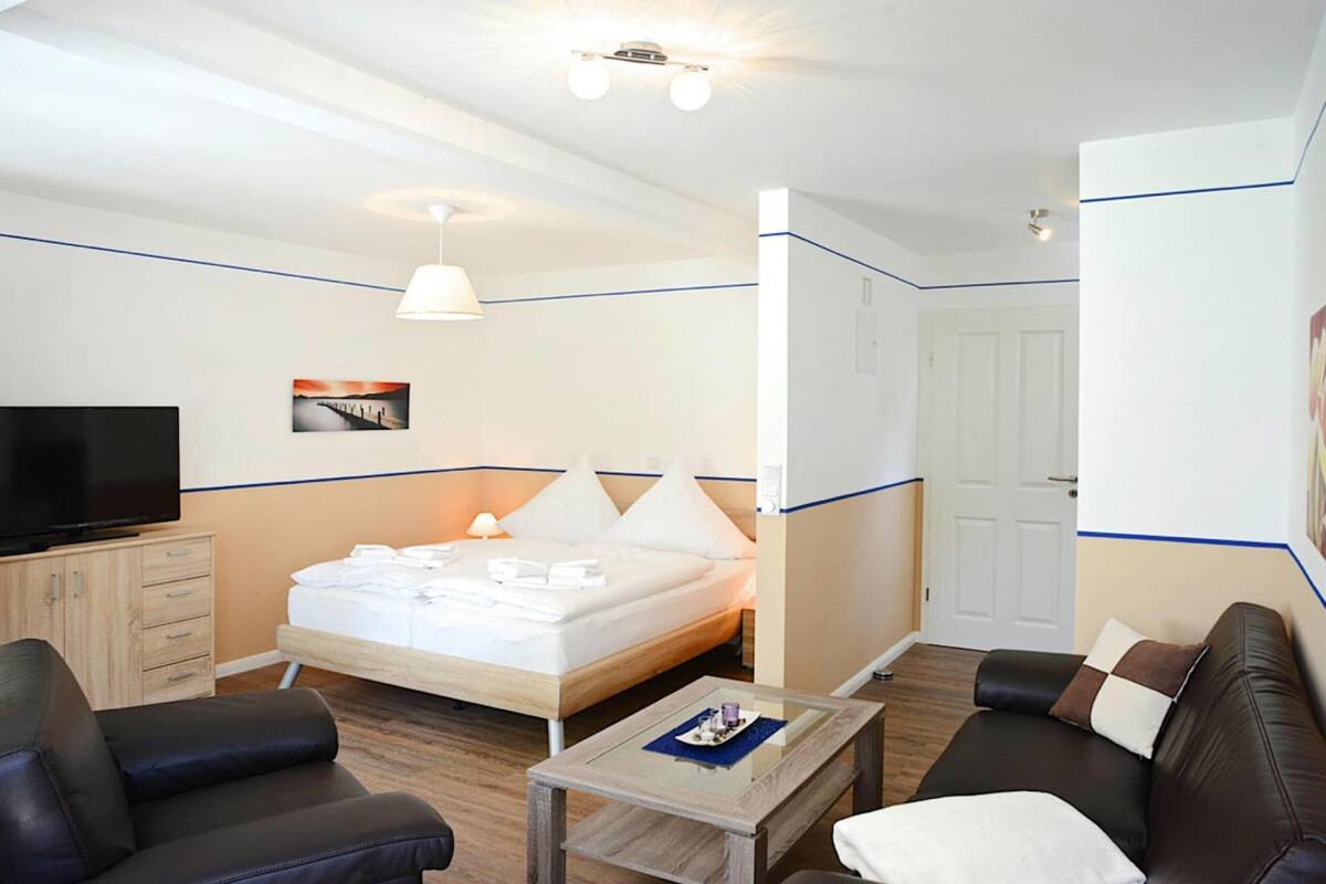 A hotel room with a bed, a television, a desk, a sofa, and a door.