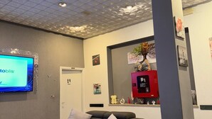 Een moderne woonkamer met een hoekbank, een flatscreen televisie en een decoratief plafond.