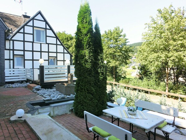 A traditional half-timbered house with a garden patio featuring a table and benches. - Apartment in Schmallenberg-oberkirchen With Terrace (Schmallenberg)