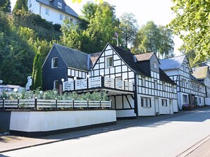 A traditional half-timbered house with a balcony, situated on a street with a sidewalk and a fence in front. - Apartment in Schmallenberg-oberkirchen With Terrace (Schmallenberg)