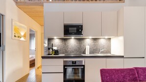 A modern kitchen with white cabinets, a microwave, a coffee maker, and an oven. - Large Apartment in Sankt Georgen With Balcony (Bruck an der Grossglocknerstrasse)