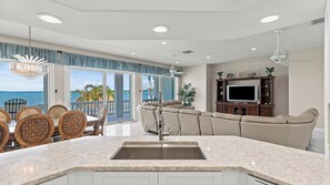 A modern kitchen with a marble countertop, a built-in sink, and a dining area with wicker chairs. - Sea Forever Sunsets On the Ocean all year round 4 bed 3 bath, dock and pool (Marathon)