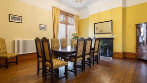 A dining room with a wooden table and chairs, a chandelier, a fireplace, and a mirror on the wall. - Host Stay Chatsworth Townhouse II (Carlisle)