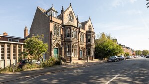 A historic building with a prominent corner entrance, large windows, and a brick facade. - Host Stay Chatsworth Townhouse II (Carlisle)