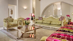 A spacious living room with a green sofa, two ornate armchairs, a glass coffee table, and a large mirror. - New Domus Historic Rome Palazzo Modern Luxury Near Piazza Navona (Rome)