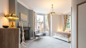 A bedroom with a bed, a bench, a radiator, a fireplace, and a window with curtains. - Host Stay Chatsworth Townhouse I (Carlisle)