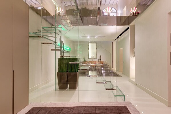Un intérieur moderne avec un escalier en verre, un comptoir d’accueil et un design minimaliste.