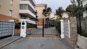 A gated entrance to a residential building with a stone wall and metal gate. - 5-minute walk to beaches, shops, sea view, air-conditioning, pool, 79 m2 T3, garage. (Cavalaire-sur-Mer)
