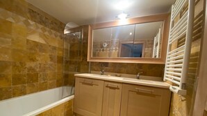 A bathroom with a bathtub, a sink, and a mirror. - 5-minute walk to beaches, shops, sea view, air-conditioning, pool, 79 m2 T3, garage. (Cavalaire-sur-Mer)