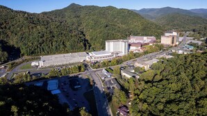 An aerial view of a campus with multiple buildings, roads, and surrounding forested hills. - Lady Luck Lodge -Mountain View-Fire Pit-Open Covered Porch-Wifi (Whittier)