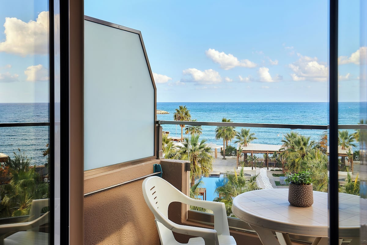 Un balcón con vista al océano, una piscina y palmeras.