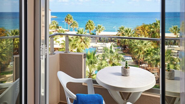 Un balcone con vista sull'oceano, un tavolo rotondo con una pianta in vaso e una sedia con un asciugamano.