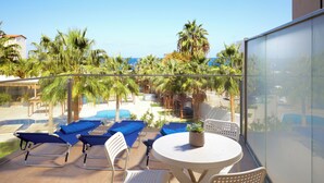 Un balcone con piscina, poltroncine blu, un tavolo e sedie bianche.