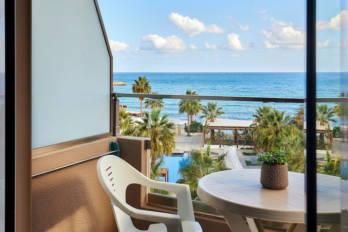 Een balkon met uitzicht op de oceaan, een zwembad en een tafel met een bloempot.