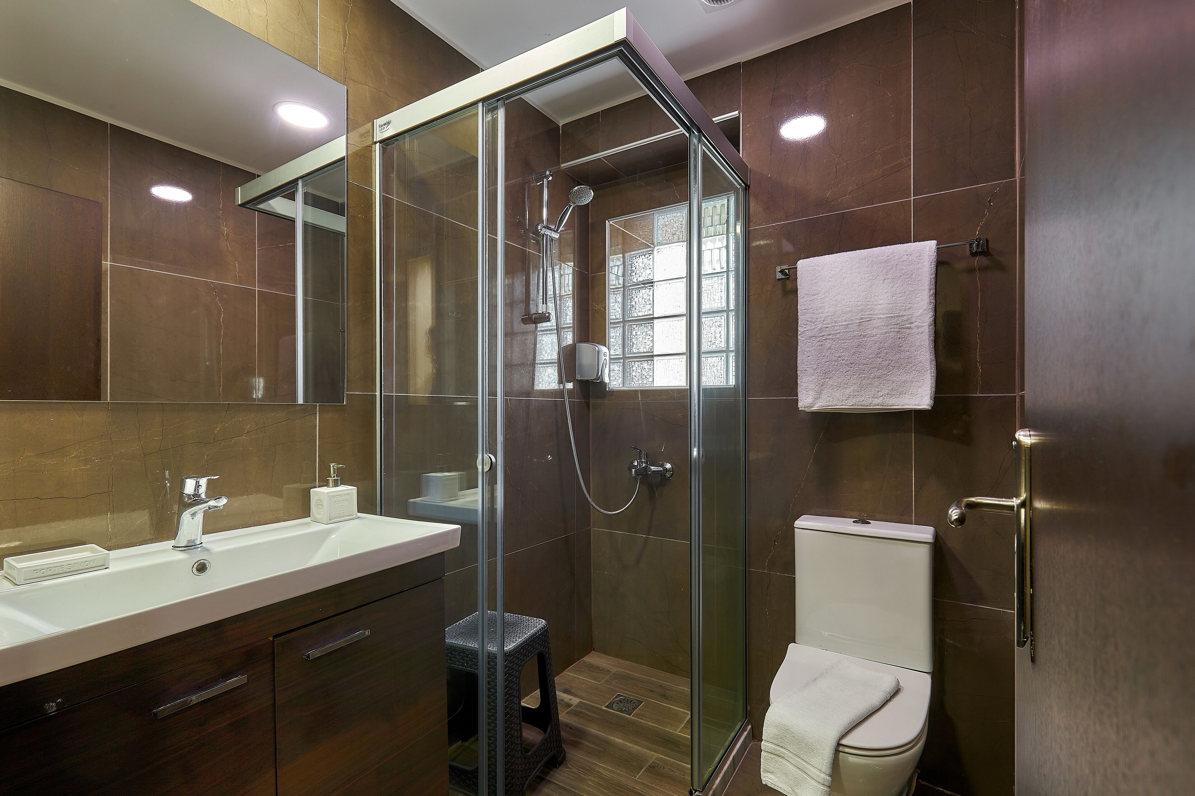 Une salle de bain moderne avec une douche à parois de verre, un lavabo blanc et des toilettes.