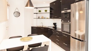 A modern kitchen with dark cabinetry, a stainless steel refrigerator, and a white dining table with chairs. - Comfortable Apartment in Athens Downtown (Athens)