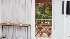 A room with a wooden table and chairs, a white curtain, and a view of a balcony with plants. - Comfortable Apartment in Athens Downtown (Athens)