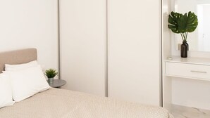 A modern bedroom with a bed, a bedside table with a plant, a dresser, and a large mirror. - Comfortable Apartment in Athens Downtown (Athens)