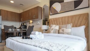 Une chambre d’hôtel avec un grand lit, un bureau et une kitchenette.
