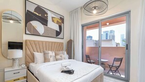 Une chambre moderne avec un grand lit, un balcon offrant une vue sur la ville et une œuvre d’art contemporaine au-dessus du lit.