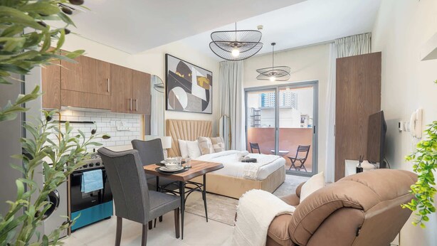 Une chambre d’hôtel moderne dotée d’un coin repas, d’une kitchenette et d’un grand lit.