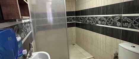 Et badeværelse med vask, toilet og bruseområde.