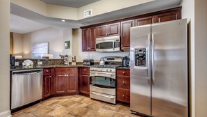 A modern kitchen with dark wooden cabinets, stainless steel appliances, and a tiled floor. - 🌊Oceanfront~Lazy River~Awesome Amenities~ North Beach Resort 210🌊 (North Myrtle Beach)