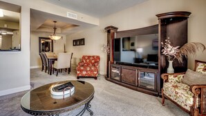 A living room with a round coffee table, a floral armchair, a sofa, a TV, and a dining area with chairs and a table. - 🌊Oceanfront~Lazy River~Awesome Amenities~ North Beach Resort 210🌊 (North Myrtle Beach)