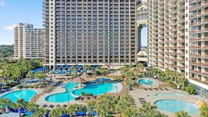 A hotel with multiple high-rise buildings, a central pool area with multiple pools, and surrounding greenery. - 🌊Oceanfront~Lazy River~Awesome Amenities~ North Beach Resort 210🌊 (North Myrtle Beach)