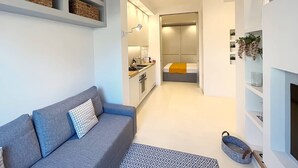 A modern living room with a grey sofa, a patterned rug, and a pet bed. - Solemar Sicilia - White Loft (Palermo)