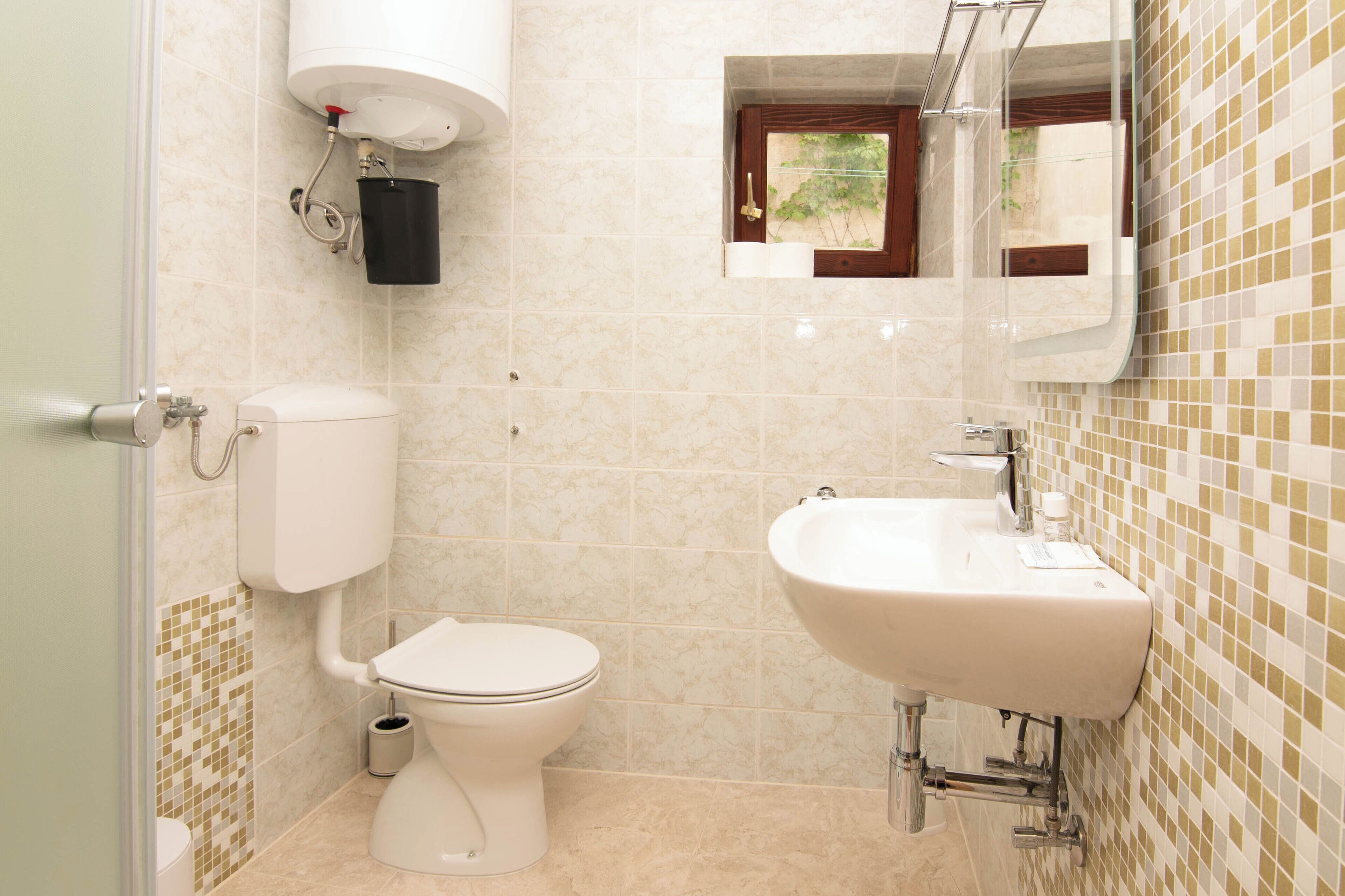 A bathroom with a toilet, sink, and a mirror above the sink.