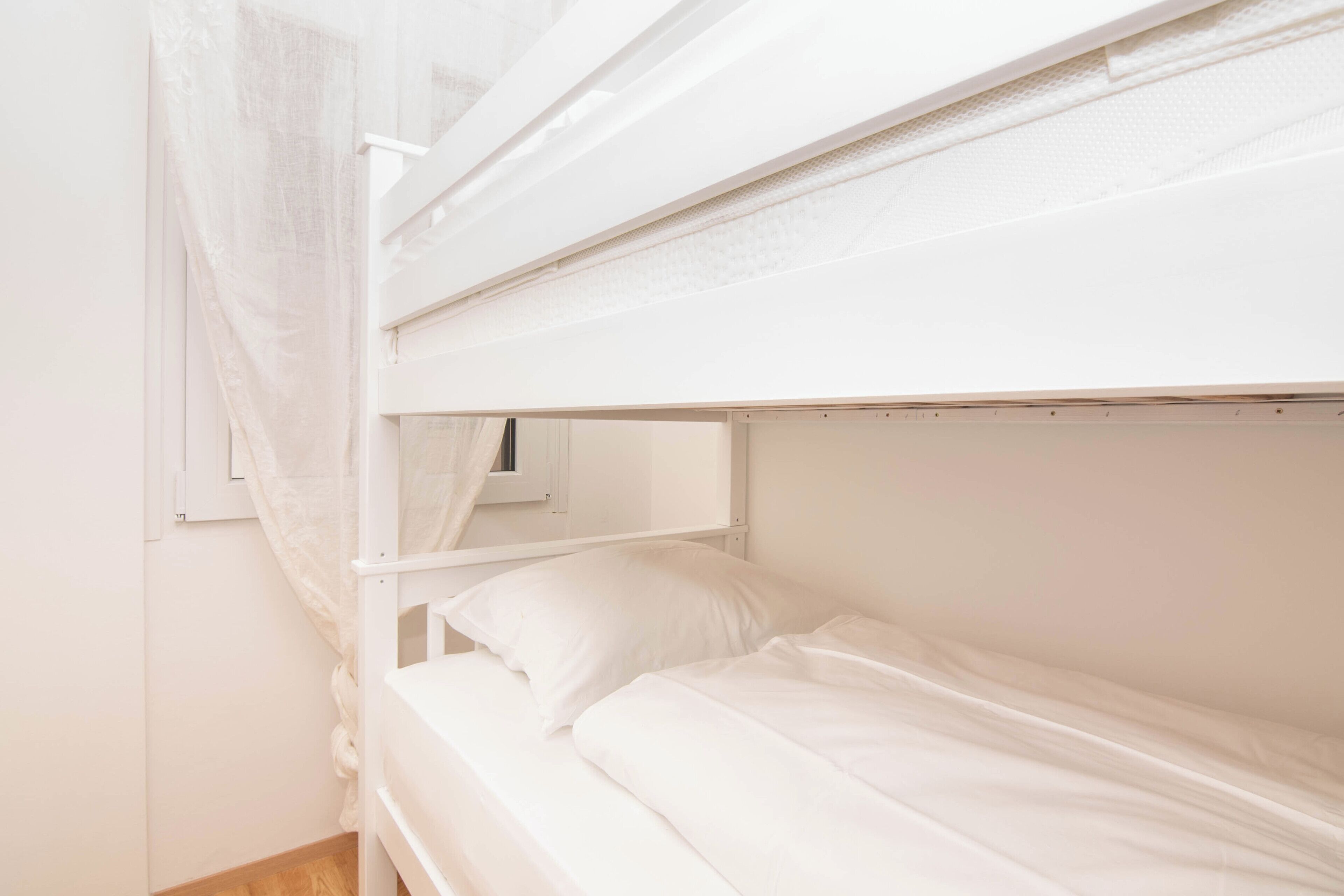 A bunk bed with white bedding and a mosquito net.
