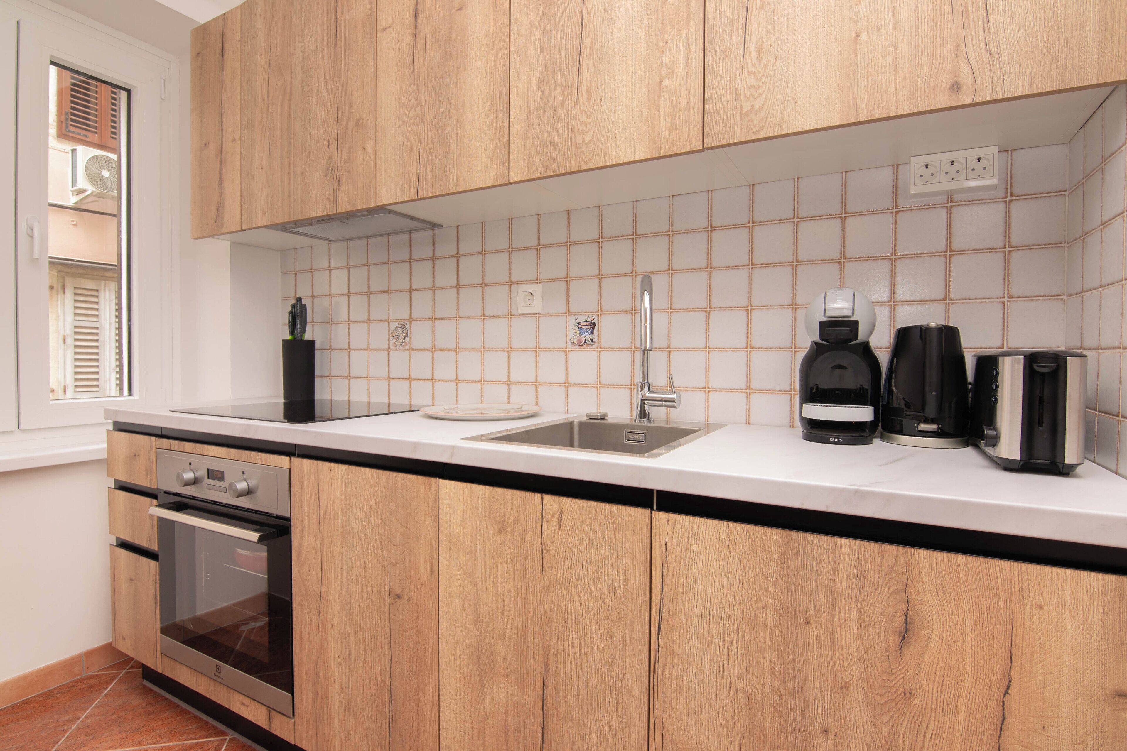 A modern kitchen with wooden cabinets, a stainless steel sink, and a built-in oven.
