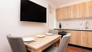 A modern kitchen with wooden cabinets, a tiled backsplash, and a dining area with a wooden table and grey chairs.