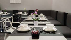 A dining area with tables set for tea service, featuring white teacups, saucers, and a black tray with utensils. - 7 Inn Spanish Steps (Rome)