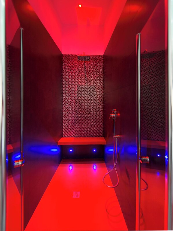 Una habitación con alfombra roja, pared con diseño y una zona de escenario con iluminación azul.