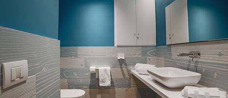 Une salle de bain moderne équipée de toilettes, d’un bidet et d’un grand miroir.