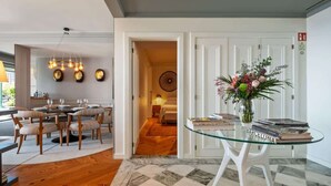 A modern interior with a dining area, a glass table with books, and a hallway leading to a bedroom. - Luxury Oceanfront at Reid's Gardens (Funchal)