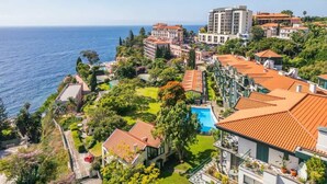 A coastal hotel with multiple buildings, a swimming pool, and a view of the sea. - Luxury Oceanfront at Reid's Gardens (Funchal)
